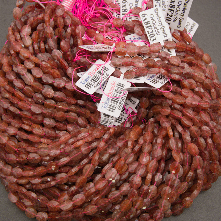 A bundle of faceted strawberry quartz oval bead strands with Tejas Beads tags