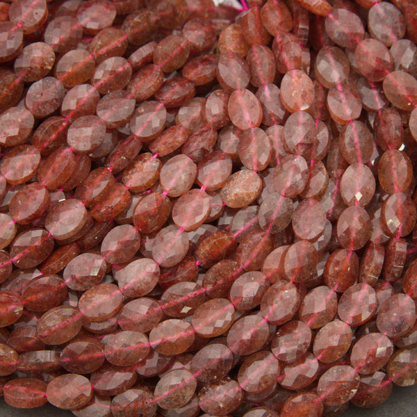 Close-up of faceted strawberry quartz oval beads showing translucent pink stone with tiny red flecks