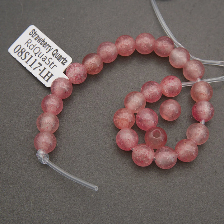 Strawberry quartz beads on a gray background with a label.