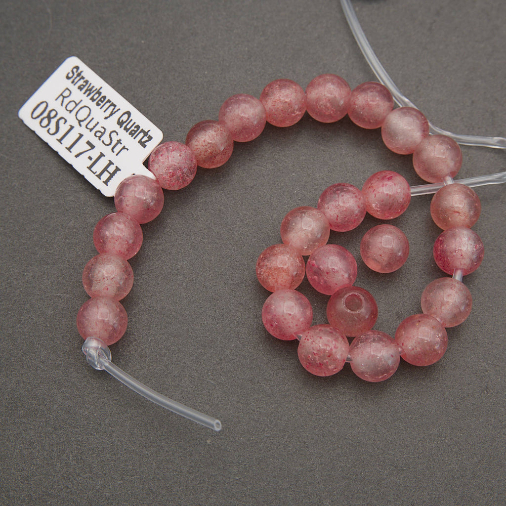 Strawberry quartz beads on a gray background with a label.