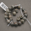 grey speckled beads on a string with large holes.