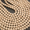 Beige wooden beads arranged in loops on a dark gray background.
