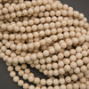 A pile of small, round, light beige wooden beads on a dark gray background.