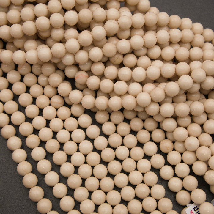 A pile of small, round, light beige wooden beads on a dark gray background.
