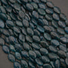 Close-up of dark green teardrop-shaped beads on a gray background