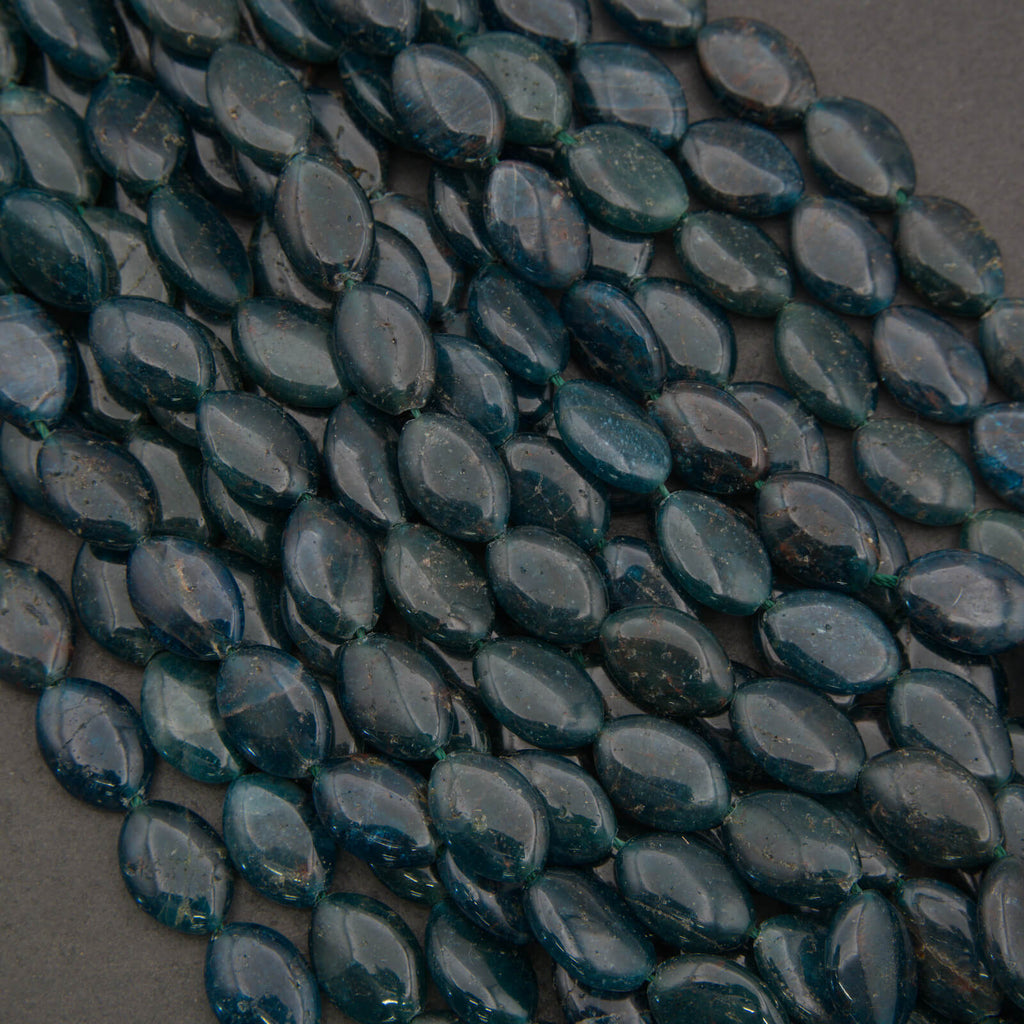 Close-up of dark green teardrop-shaped beads on a gray background