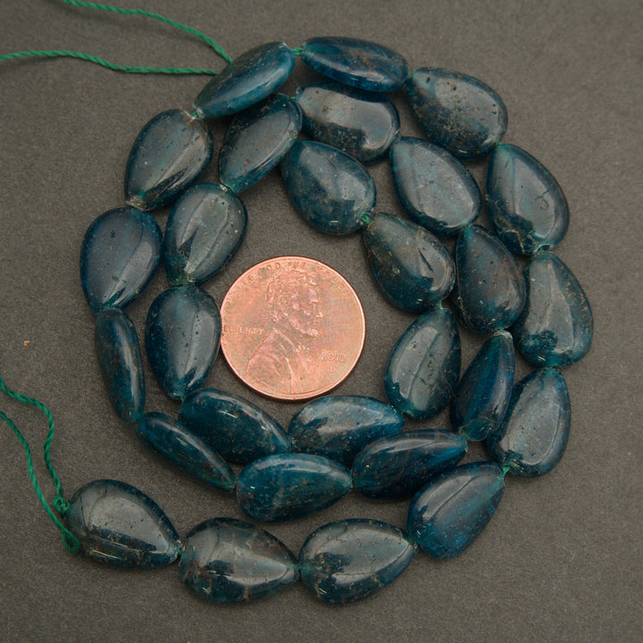 Blue beads arranged in a circular pattern with a penny for size comparison on a gray background