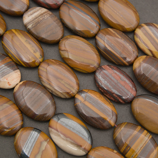 Polished Tiger Iron oval gemstone beads featuring natural bands of gold, brown, gray, and red mineral layers.