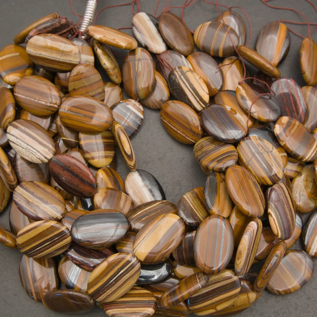 Smooth Tiger Iron oval stone beads displaying earthy tones and layered banding with subtle chatoyant highlights.