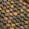 Rows of faceted tiger's eye star beads on a gray background in honey, caramel and chocolate