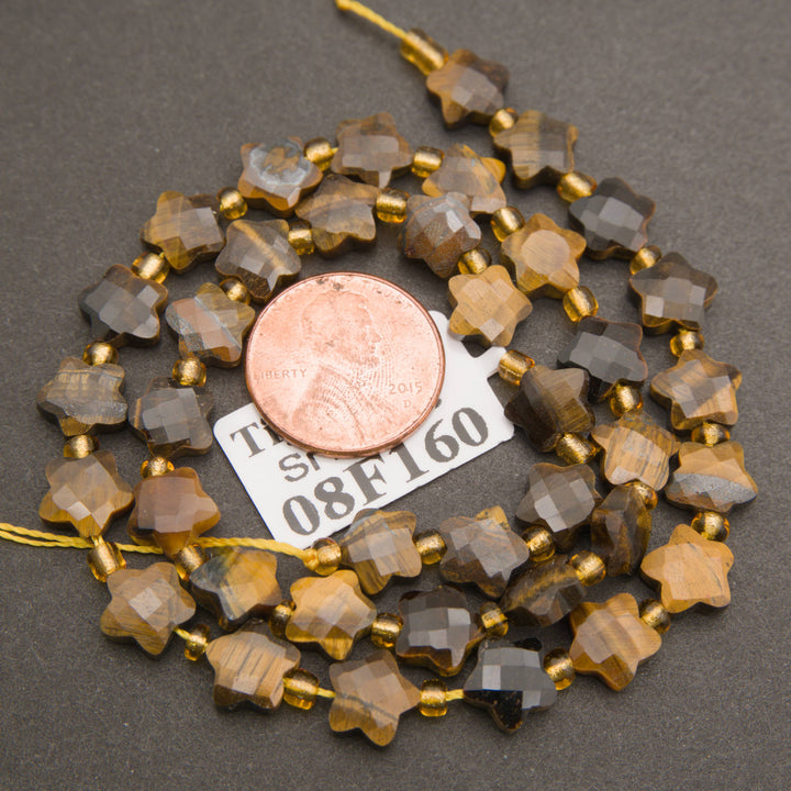 A strand of faceted tiger's eye star beads coiled around a penny for scale