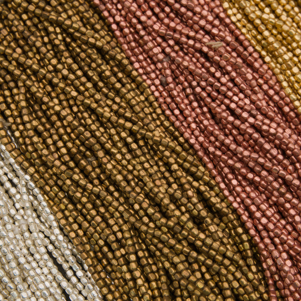 Close-up of multicolored beaded fabric with brown, pink, and beige tones.