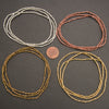Four sets of beaded necklaces in silver, copper, and gold on a dark surface with a penny for scale.