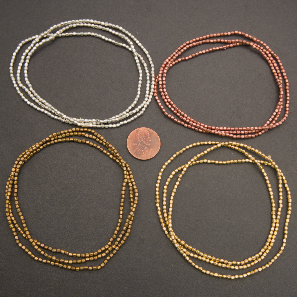 Four sets of beaded necklaces in silver, copper, and gold on a dark surface with a penny for scale.
