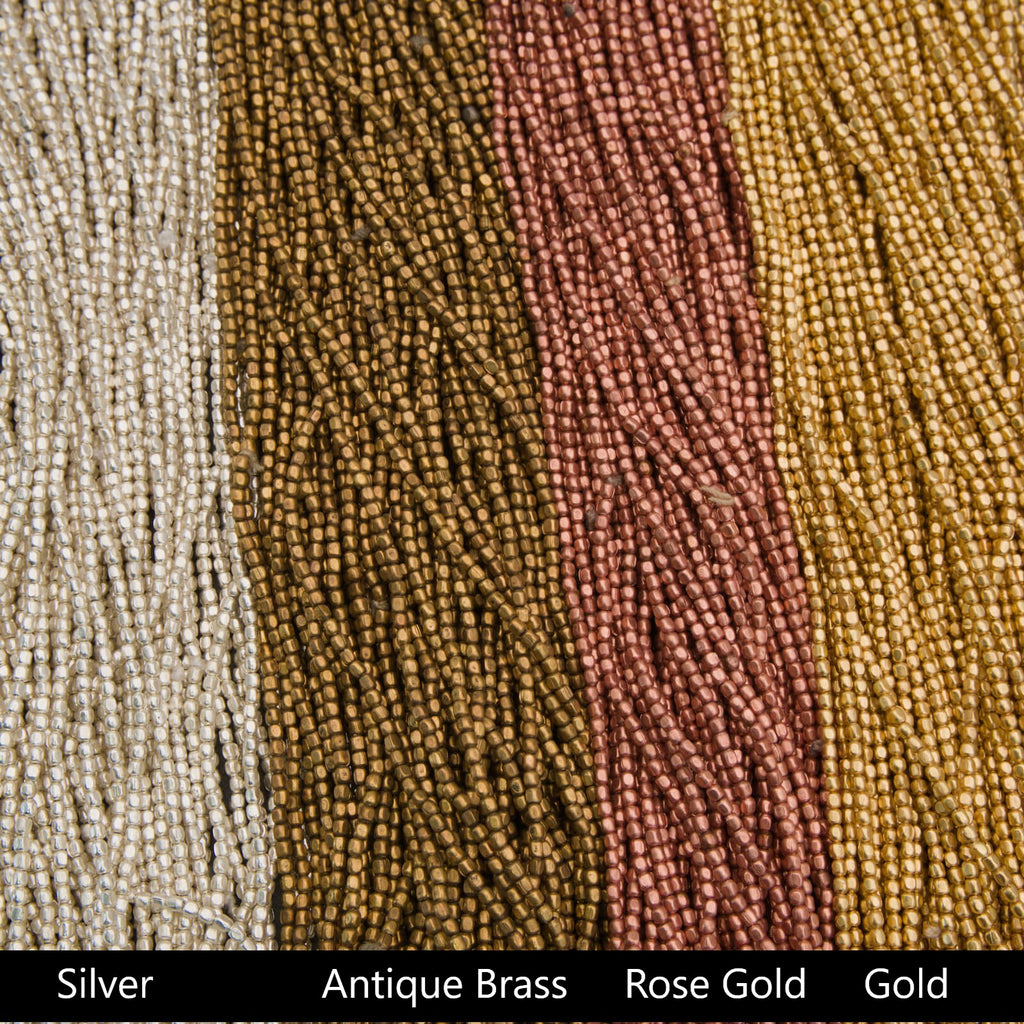 Close-up of silver, antique brass, rose gold, and gold beads arranged in a row.