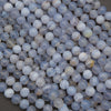 A pile of small round translucent beads in pale blue, white, and gray with some faint yellowish veining, photographed close up on a neutral surface.