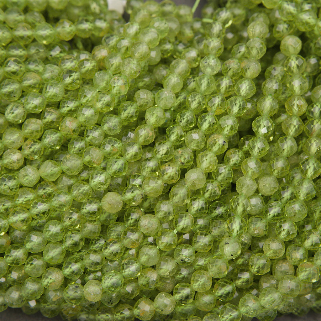 A close-up pile of faceted round beads in a translucent light green color, showing a textured, honeycomb-like surface.
