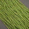 Green faceted round beads arranged in diagonal rows on a dark gray background.