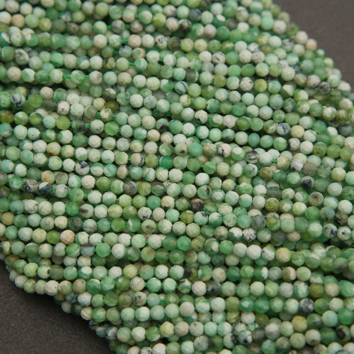 Strands of microfaceted variscite beads in soft green and cream on a gray background