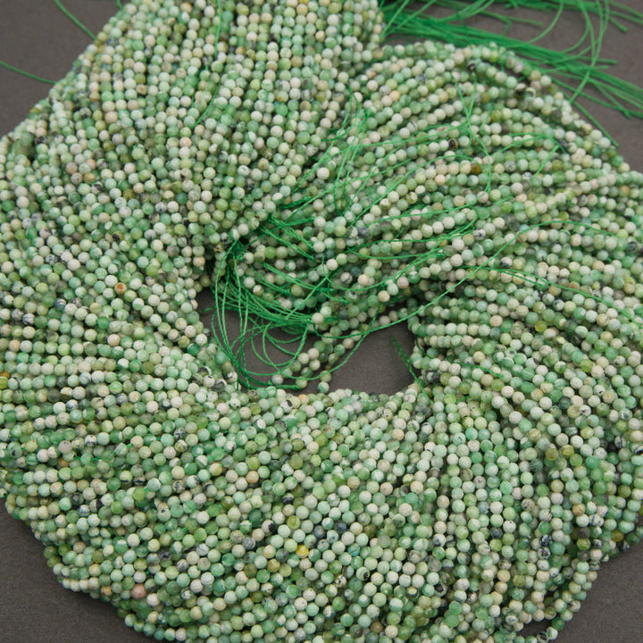 A bundle of microfaceted variscite bead strands tied with green thread