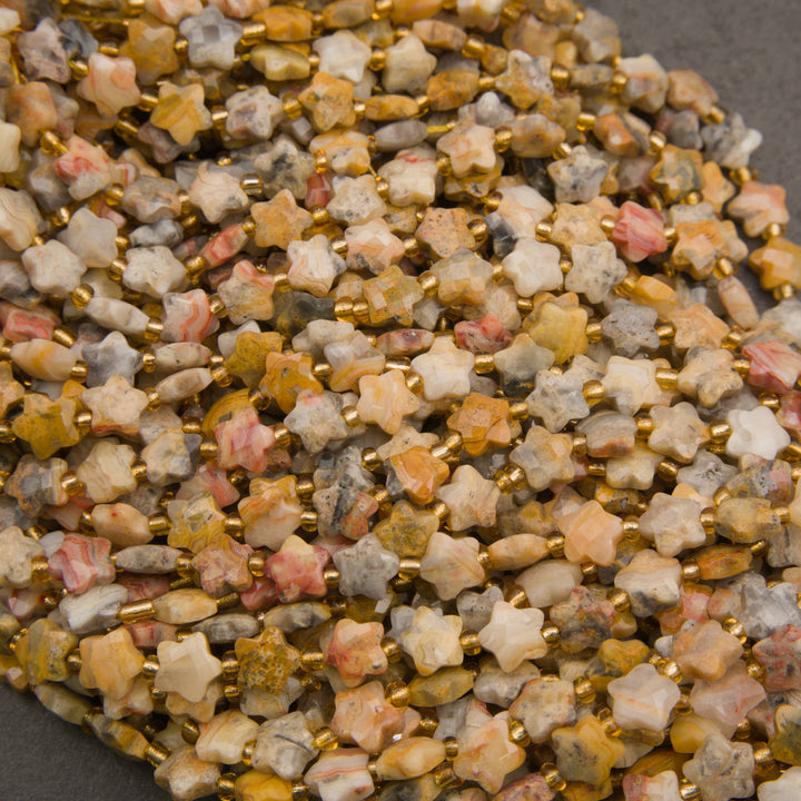 Strands of faceted yellow crazy lace agate star beads in rows on a gray background, with swirling cream and mustard bands