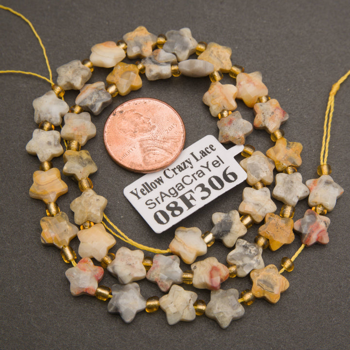 A strand of faceted yellow crazy lace agate star beads coiled around a penny for scale