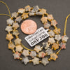 A strand of faceted yellow crazy lace agate star beads coiled around a penny for scale