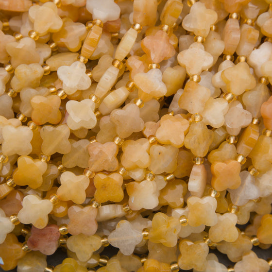Faceted yellow jade clover beads in warm golden-yellow and creamy white tones with gold spacers.