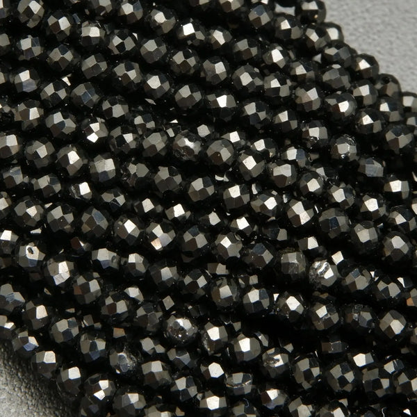 Faceted round black spinel beads on a string.
