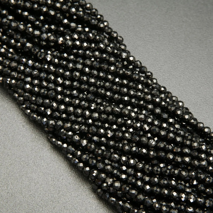 Faceted round black spinel beads on a string.