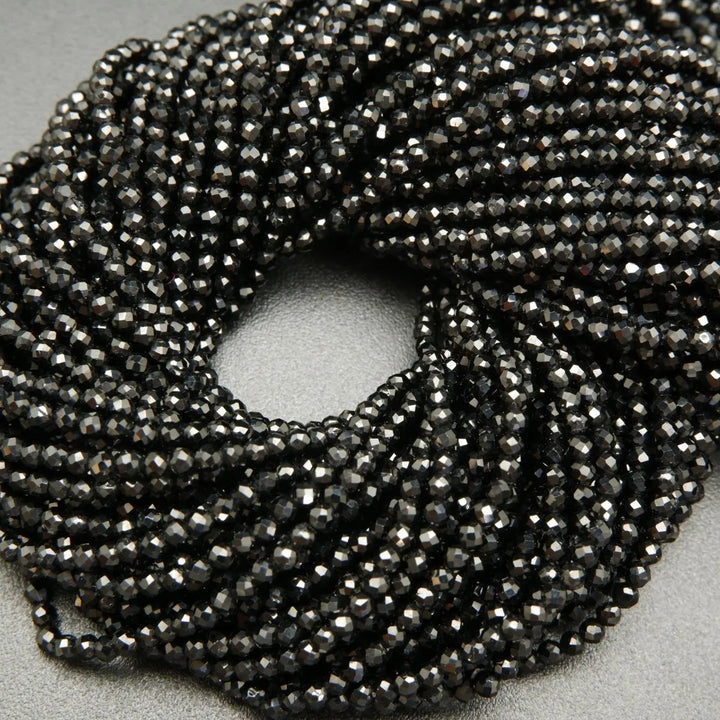 Faceted round black spinel beads on a string.