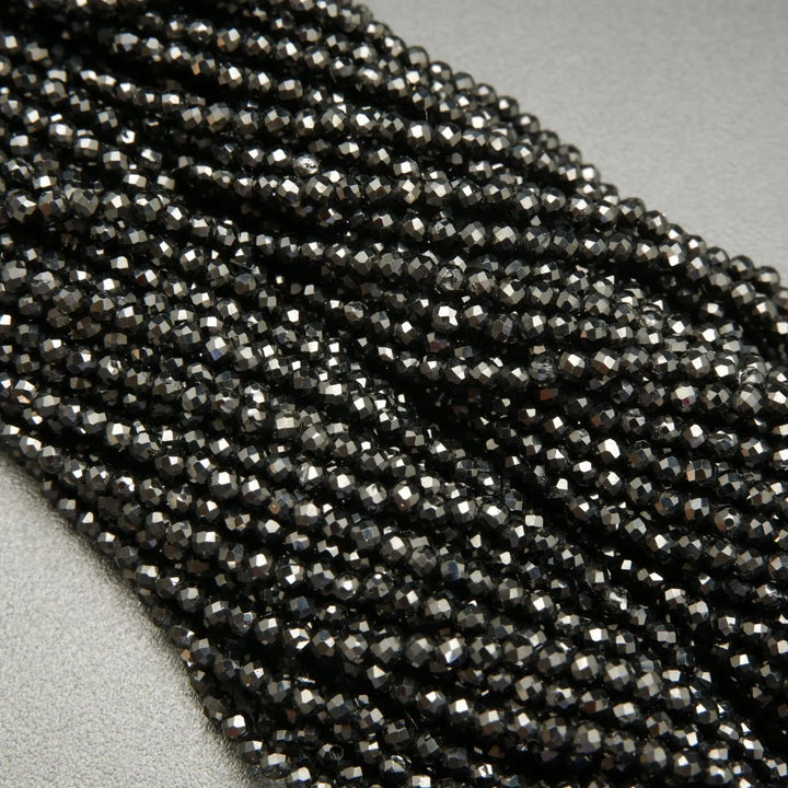 Faceted round black spinel beads on a string.