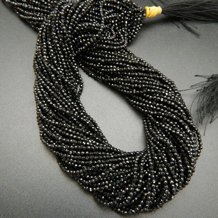 Faceted round black spinel beads on a string.