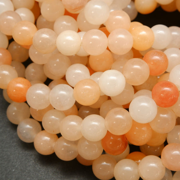 Peach Aventurine Beads showing a mix of hues from light to dark peach, with an almost orange appearance.