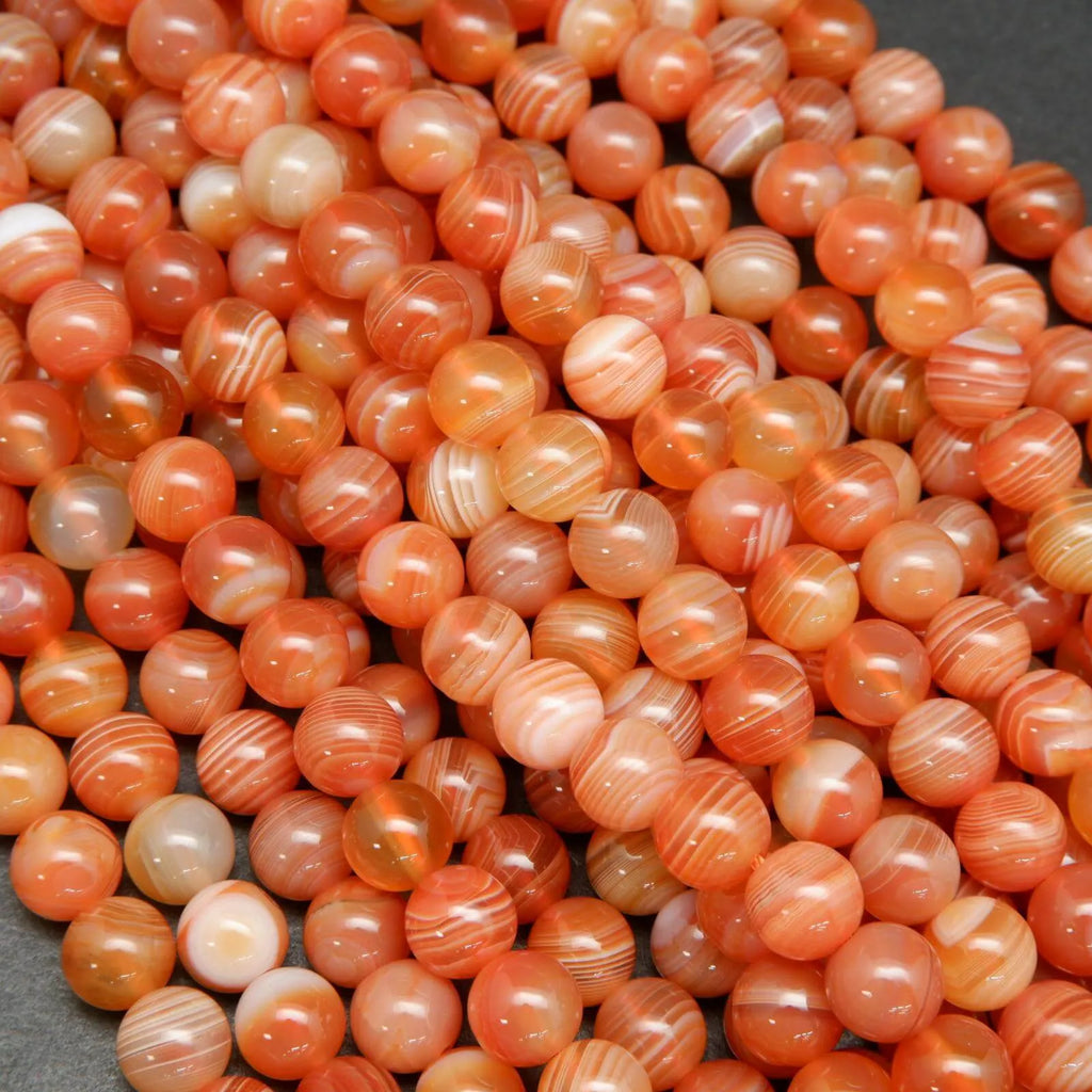 Peach and red Botswana agate beads with wavy white stripes.