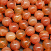 Peach and red Botswana agate beads with wavy white stripes.