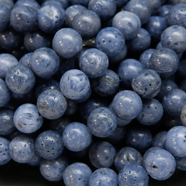 A close-up pile of round, polished blue-gray beads with a porous, stone-like texture.