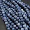 A close-up pile of round, polished blue-gray beads with a porous, stone-like texture.