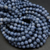 A close-up pile of round, polished blue-gray beads with a porous, stone-like texture.