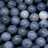 A close-up pile of round, polished blue-gray beads with a porous, stone-like texture.